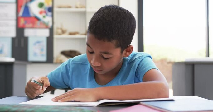 In school, a young African American student focuses on his notebook in the classroom