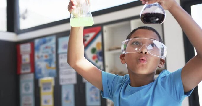 In school, in a classroom, a young Asian student examines chemical reactions