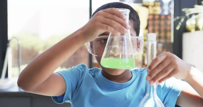 In a school setting, in a classroom, an African American student conducts a science experiment