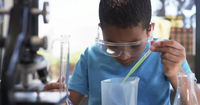 In a school science lab classroom, an African American student conducts an experiment