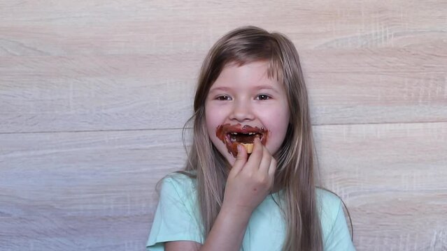 Laughing happy little girl eating chocolate dirty face