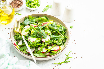 Spring salad with spinach, arugula, radish with olive oil and seeds.