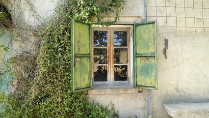 The window with metal shutters of an ancient abandoned house in the countryside.