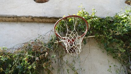 An old basketball hoop on the wall of an old abandoned country house.