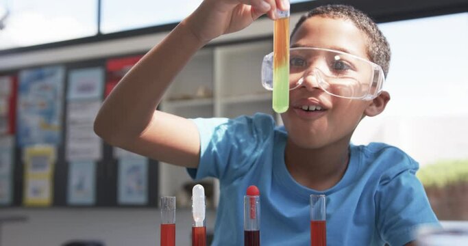 In school, a young African American student examines a test tube in the classroom