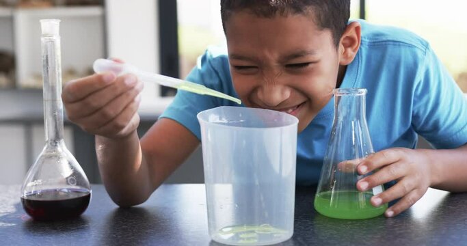 In a school science lab classroom, a young African American student conducts an experiment