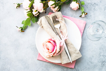 White plate, cutlery and wine glass with pink flowers. Spring table settong. Flat lay with copy space. - Powered by Adobe