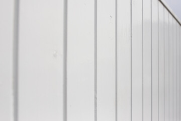 Close-up across a painted white fence with vertical panels