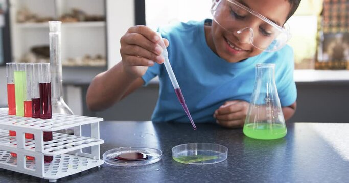 In a school laboratory classroom, a young African American student conducts an experiment