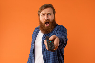 Shocked Bearded Man Watching Television Pointing Remote Controller In Studio - 768177171