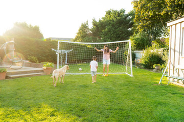 Young mother and son plays soccer with dog and have fun together. Happy family playing football...