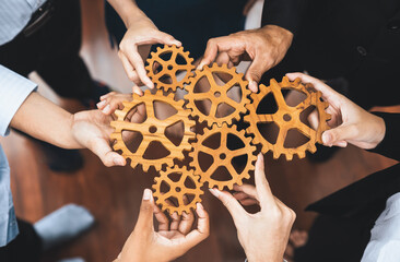 Office worker holding cog wheel as unity and teamwork in corporate workplace concept. Diverse colleague business people showing symbol of visionary system and mechanism for business success. Concord