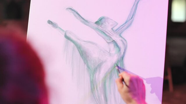 View from shoulder of creative designer in process of drawing artwork of dancer on canvas. Talented picture displaying graceful ballerina in blue colors with arms extending.