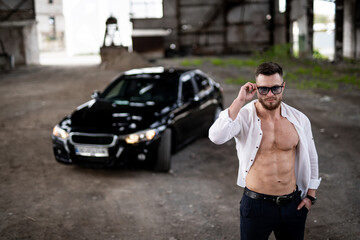 Sexy macho man with strong torso with car standing. Handsome muscular model guy.