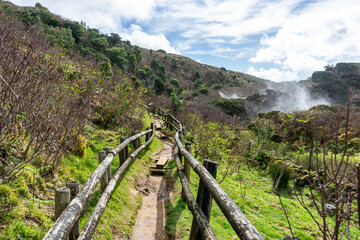 Fototapeta na wymiar Wooden footbridge winding through sulfur fumaroles in Terceira Island's furnas, Azores.