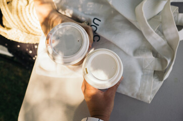two people's hands holding coffee in the sun
