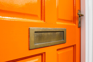 Orange front door cross section with gold letterbox and golden door handle  - obrazy, fototapety, plakaty