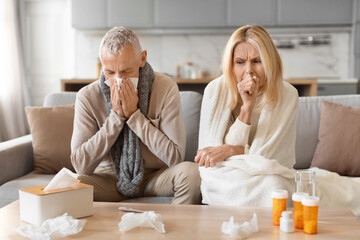 Sick couple blowing noses on couch