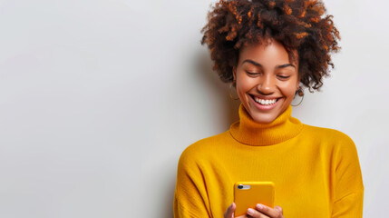 Young African American woman with yellow sweater looking at her phone