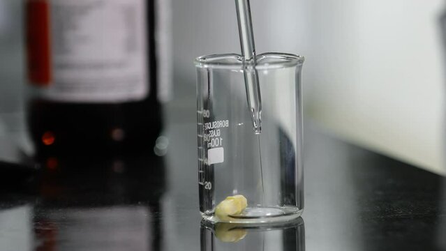 Close up scientist mixing chemicals conducting experiment science experiment in a beaker flask titration with colorful pink chemical liquid in laboratory with medical drug equipment	

