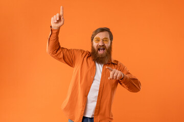 Fototapeta premium redhaired bearded man wearing sunglasses dances with cool vibes, studio