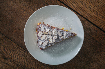 piece of almond orange cake with icing sugar on a plate