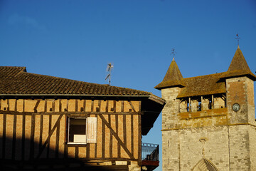 old stone church with two towers by a halftimbered house in a small french village