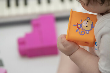 Child playfully handles blocks and other toys at childcare while sitting down. Narrow depth of...