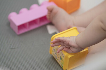 Child playfully handles blocks and other toys at childcare while sitting down. Narrow depth of...