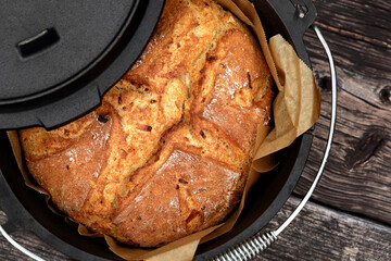 Homemade onion bread baked in a traditional Dutch oven on a rustic wooden background, top view of a...