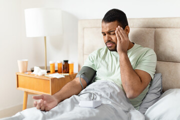 Man checking blood pressure in bed