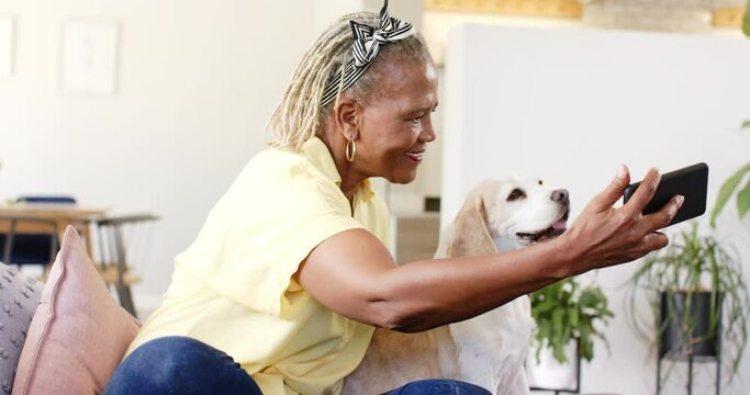 An African American senior woman is taking a selfie with her dog at home