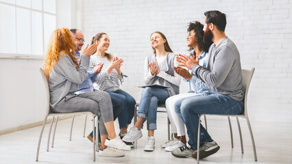 Group of happy people applauding themselves at therapy session, celebrating progress