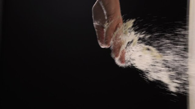 Cooking with wheal powder by hands against black background