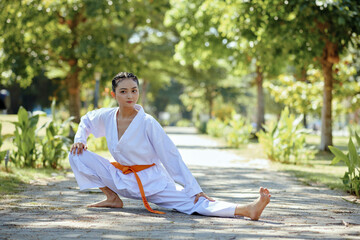 Taekwondo athlete stretching legs before working out in park