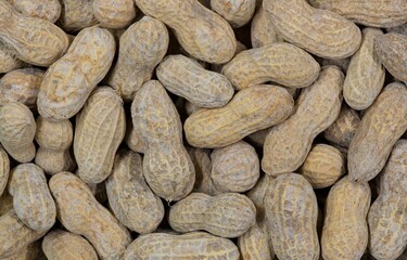 Unshelled peanuts scattered flat lay closeup food legume crop nutrition allergy farming industry concept copy space.