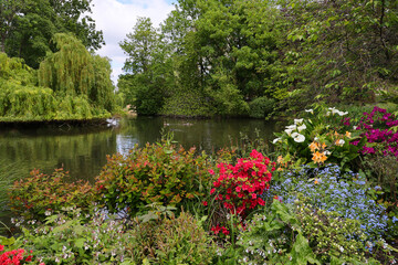 Saint James Park in London with green trees in sunny spring with many flowers by pond river, water landscape.