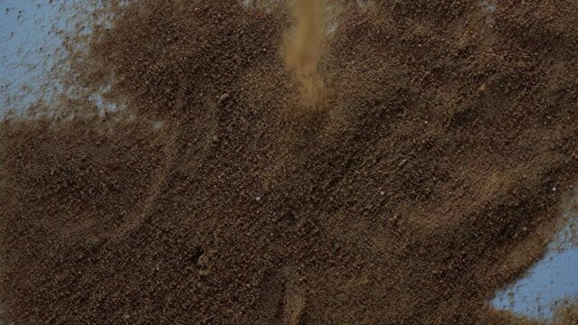 Brown powder falling from the top against black background