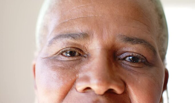 A close-up reveals a senior African American woman with warm brown eyes at home