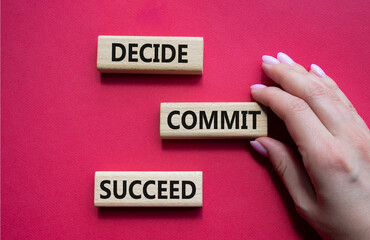 Decide Commit Succeed symbol. Concept words Decide Commit Succeed on wooden blocks. Businessman hand. Beautiful red background. Business concept. Copy space.