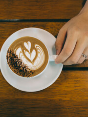cup of coffee with hand holding in the cafe