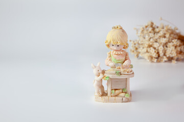 Antique decoration, girl with rabbit. In the background, a bouquet of dry white flowers on a white...