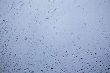 Raindrops on a window with a grey cloudy background