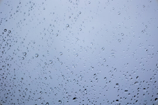 Raindrops on a window with a grey cloudy background