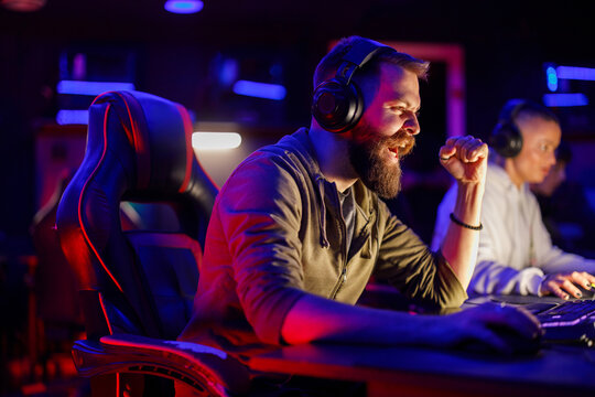 Pro bearded male gamer celebrating victory while playing online video games