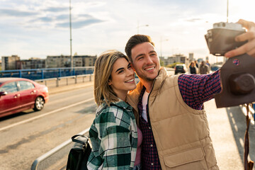 a young couple of tourists make a self portrait using a analog camera as they sightseeing