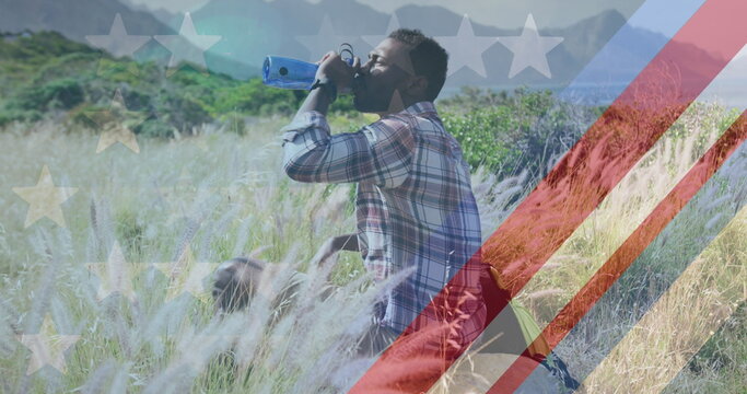 Image of american flag over african american man drinking water in mountains - Powered by Adobe