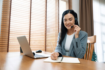 Female call center operator or customer service helpdesk staff working on workspace while talking...