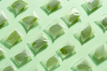  Fresh green tea leaves in individual plastic bags on vibrant green background, flat lay composition with copy space, top view © SHOTPRIME STUDIO