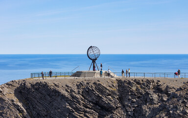 Travellers at the Northcape, Nordkap monument in Norway on a summer day. Northernmost place of the...